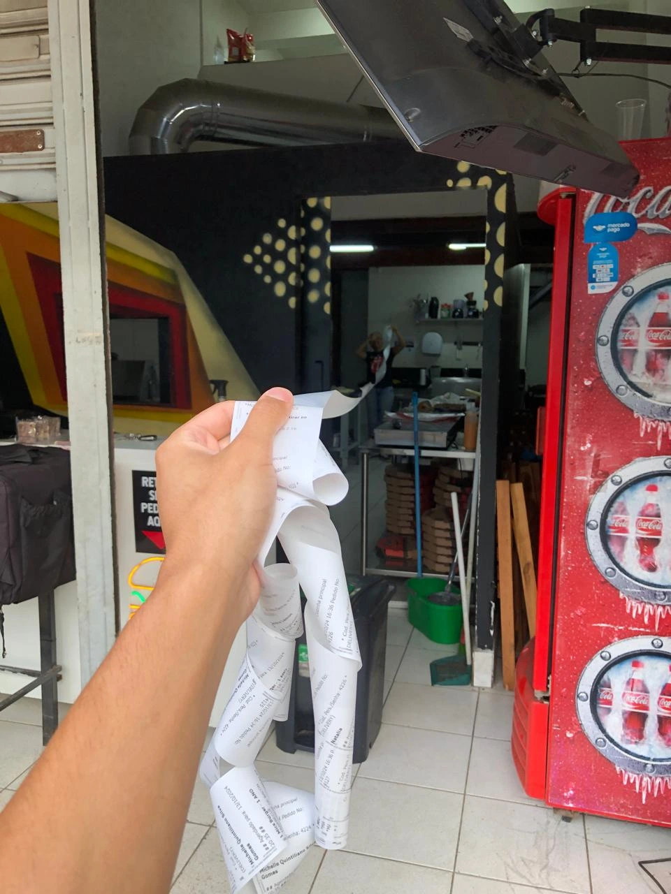 Igor segurando um grande volume de comandas na entrada da loja